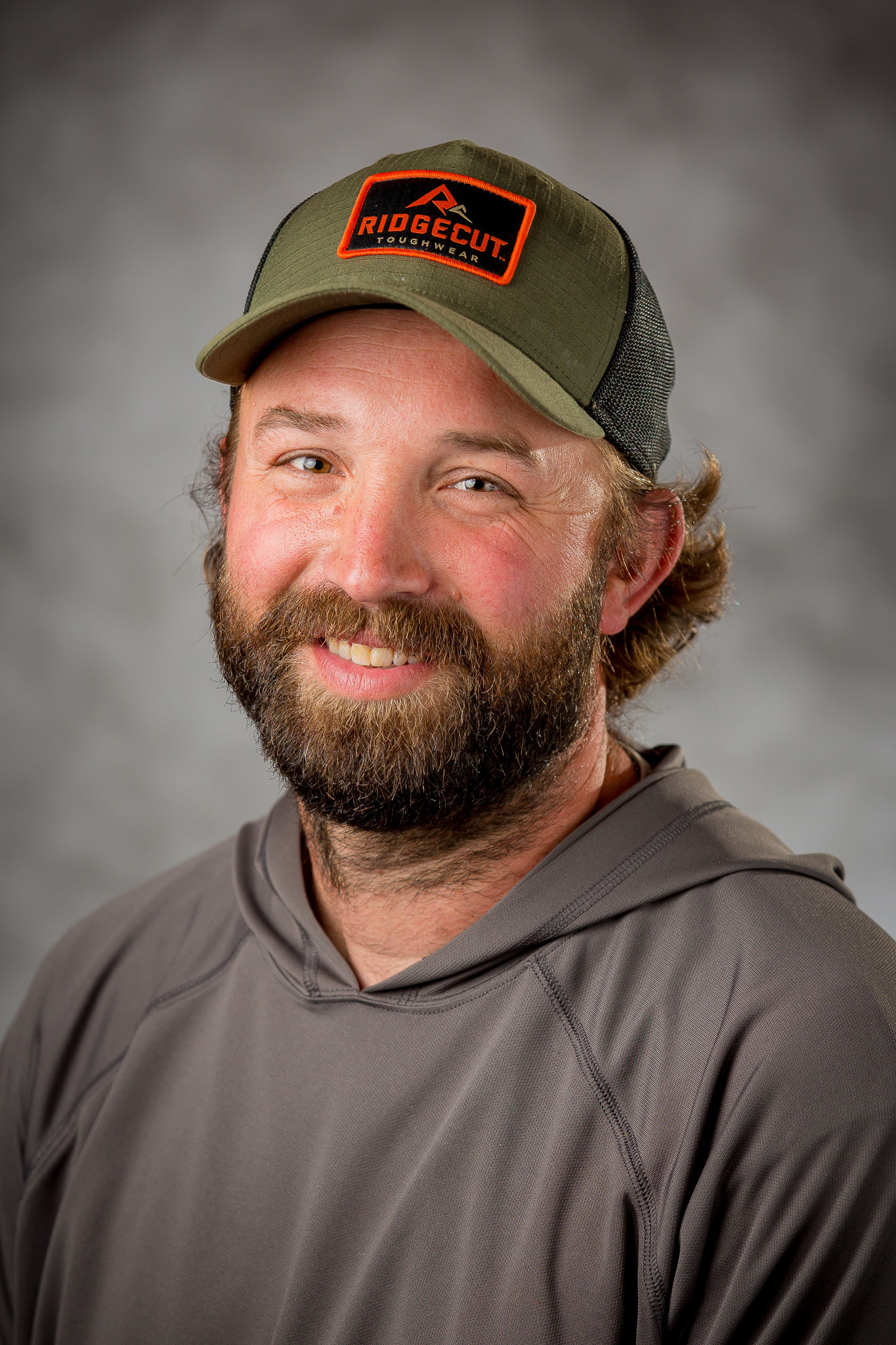 a man with a beard wearing a hat and a grey hoodie