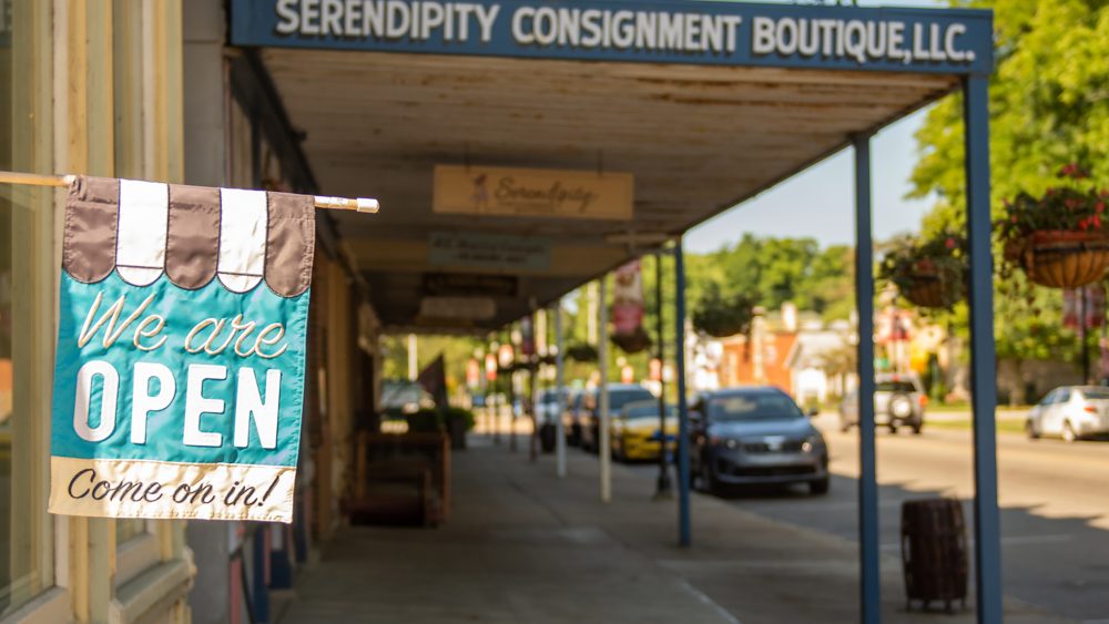 downtown businesses with a flag that says "we are open come on in!"